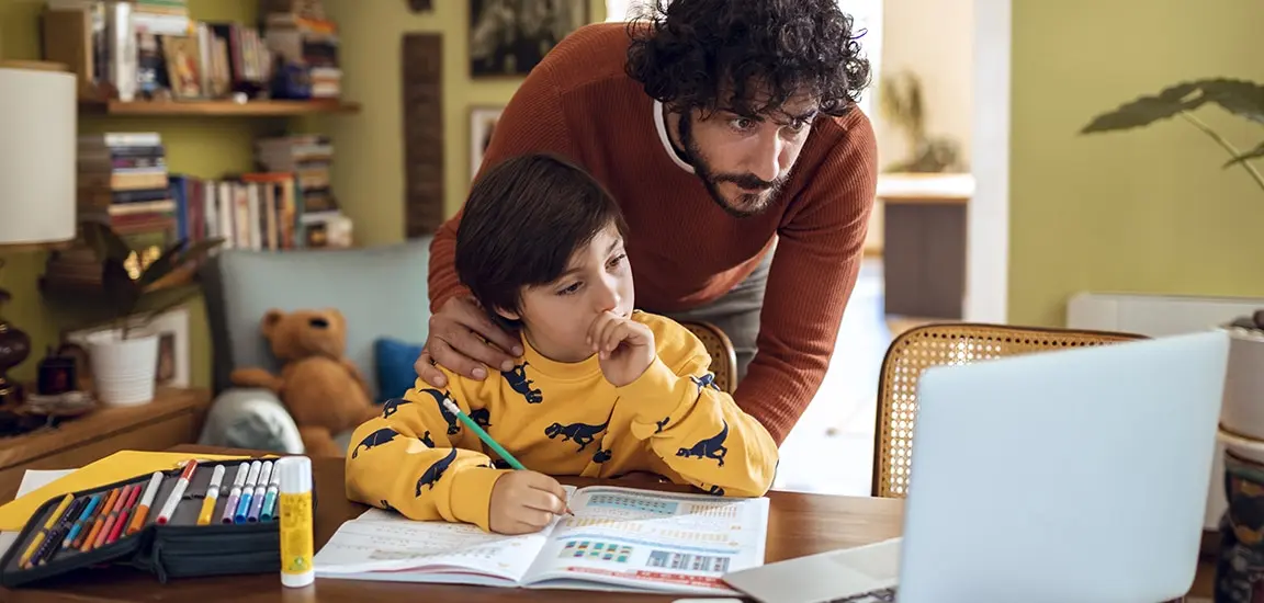 Close up of a father helping his son with schoolwork in their home