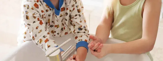 Torsos of two children holding washing hands in running bathroom sink