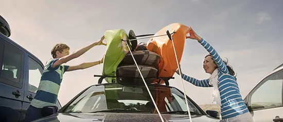People unloading canoes from top of small car