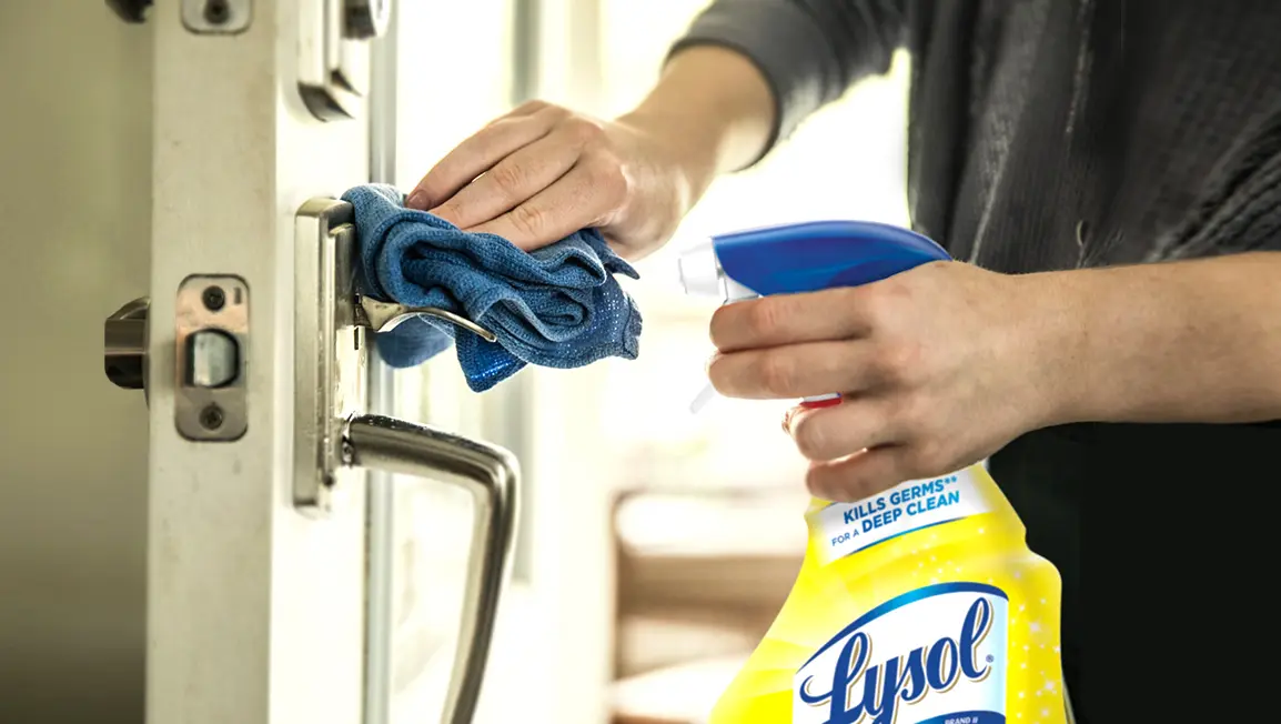 Life is messy. We’re here for it. A bottle of Lysol Multi-Purpose cleaner and a cloth being used to clean a door latch.